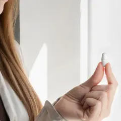 Kobieta trzyma tabletkę, która stanowi jej dzienną dawkę magnezu.