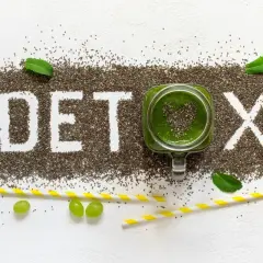 Nasiona chia tworzą napis DETOX. Zielony koktajl w słoiku i winogrona symbolizują oczyszczanie organizmu z toksyn.