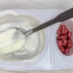 Jogurt z łyżką i czerwonymi drażetkami. Czy karagen jest szkodliwy? To pytanie nurtuje wielu konsumentów.