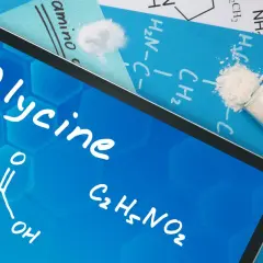 Tablet z napisem "Glycine" i wzorem chemicznym. Obok probówka z białym proszkiem. To jest glicyna, co to jest?