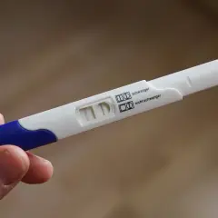 Test ciążowy z dwoma paskami, wskazujący na brak okresu i negatywny wynik.