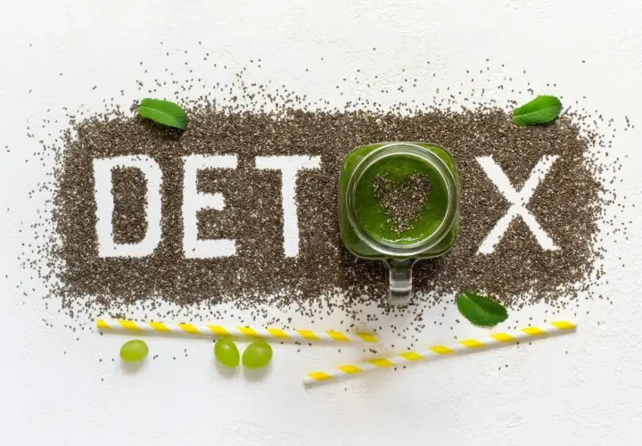 Nasiona chia tworzą napis DETOX. Zielony koktajl w słoiku i winogrona symbolizują oczyszczanie organizmu z toksyn.
