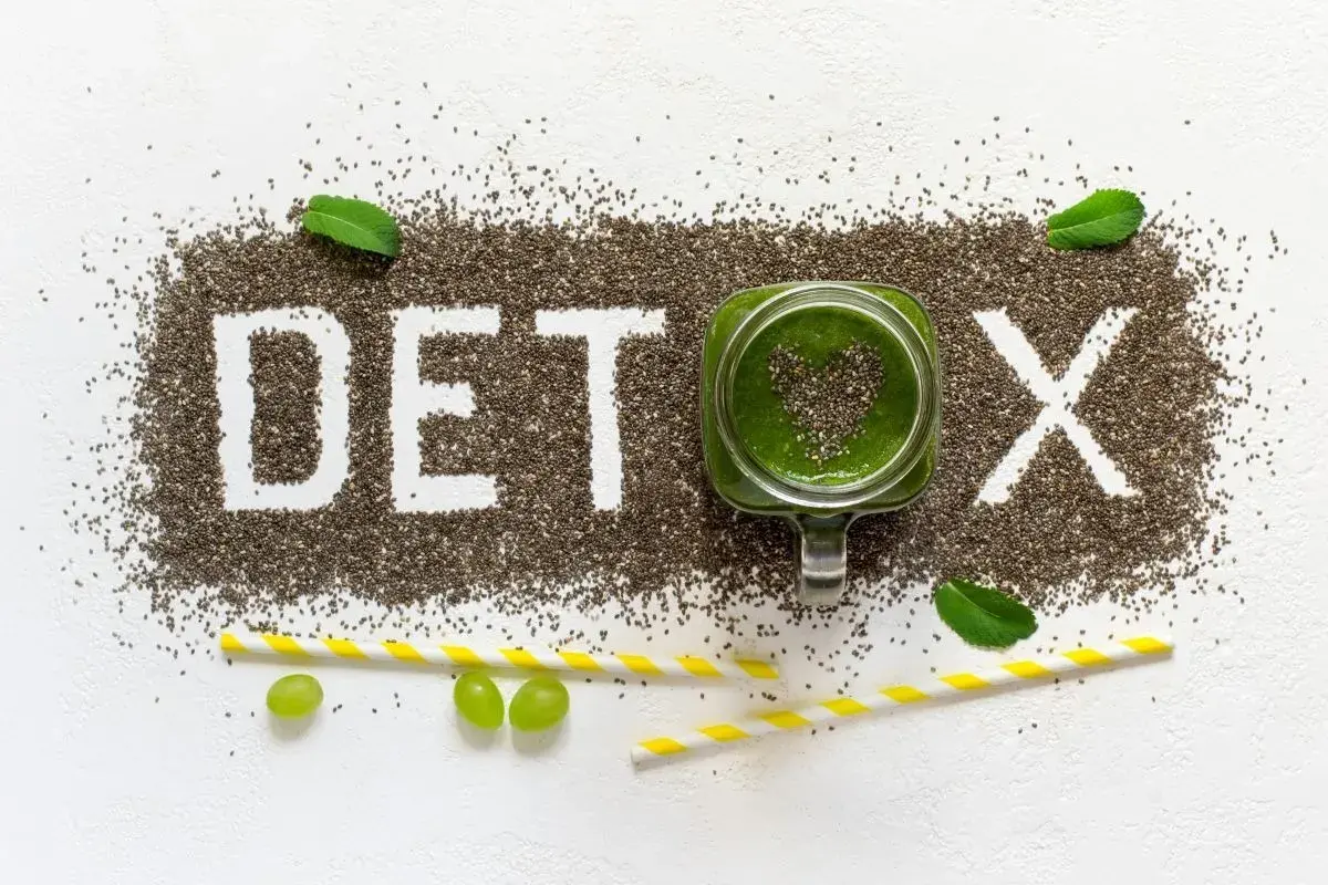 Nasiona chia tworzą napis DETOX. Zielony koktajl w słoiku i winogrona symbolizują oczyszczanie organizmu z toksyn.