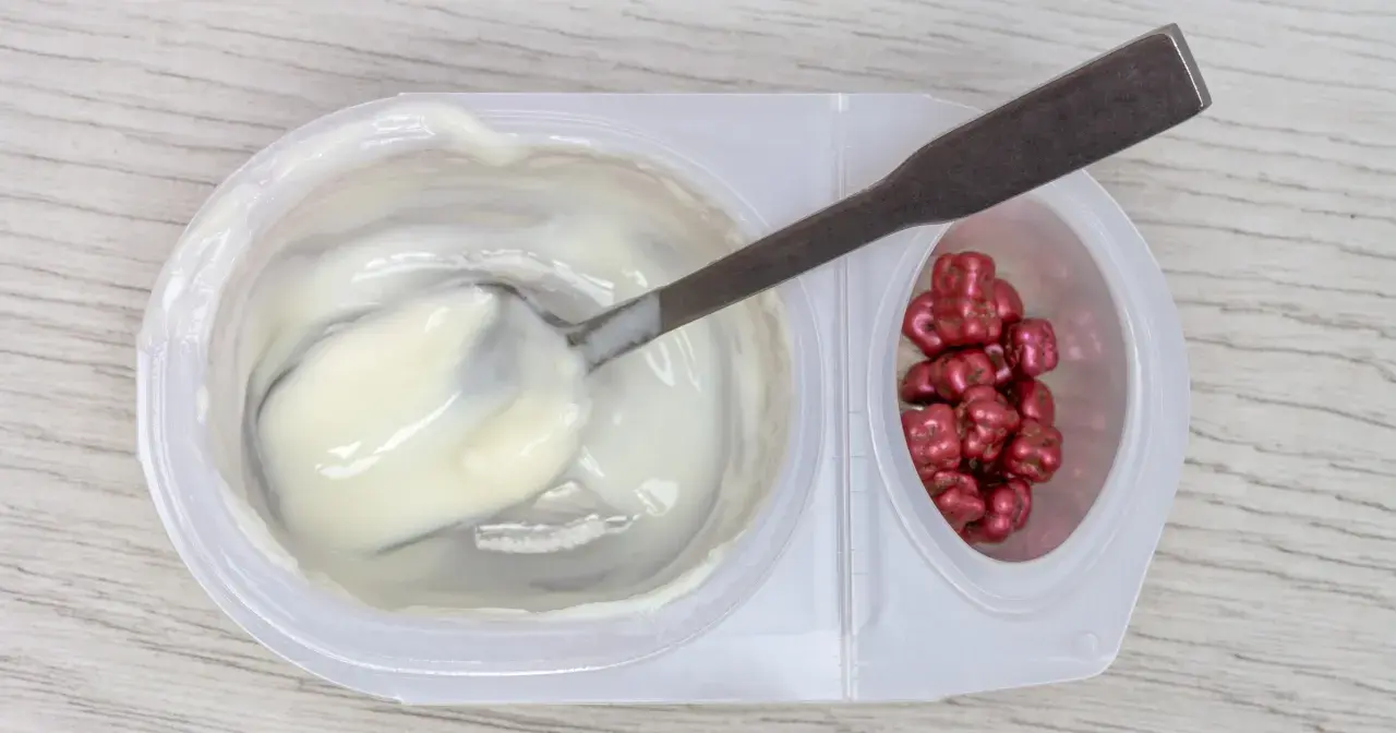 Jogurt z łyżką i czerwonymi drażetkami. Czy karagen jest szkodliwy? To pytanie nurtuje wielu konsumentów.