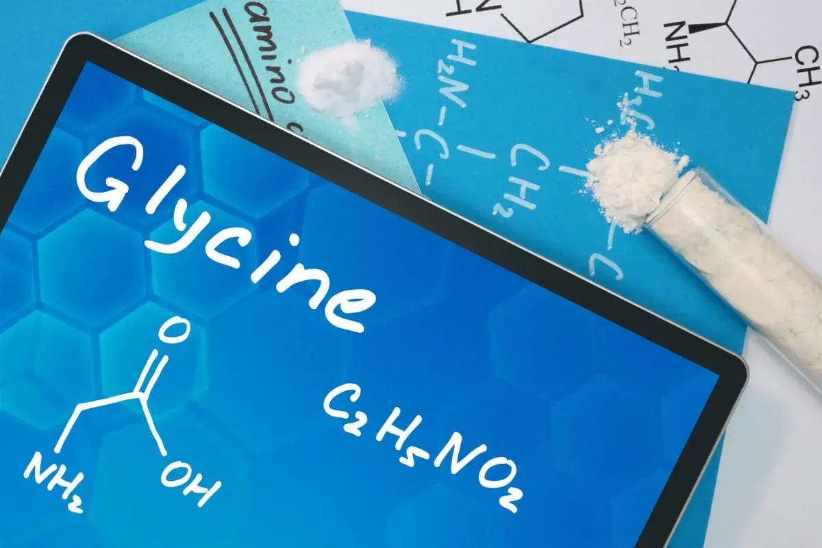 Tablet z napisem "Glycine" i wzorem chemicznym. Obok probówka z białym proszkiem. To jest glicyna, co to jest?