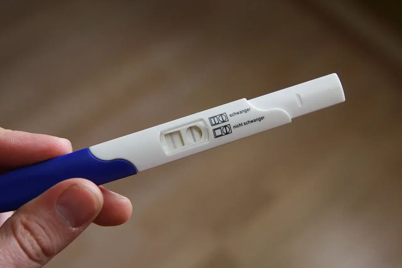 Test ciążowy z dwoma paskami, wskazujący na brak okresu i negatywny wynik.