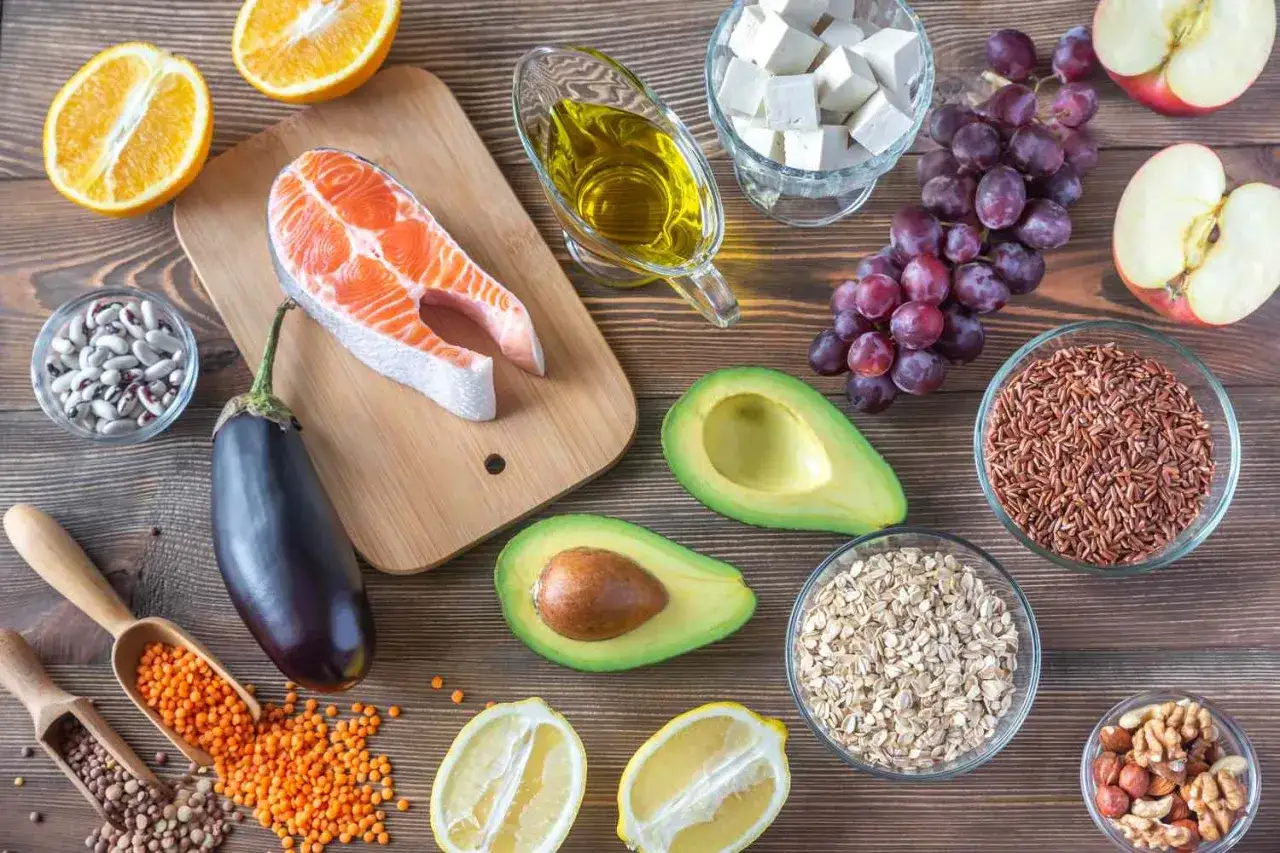 Zdrowe produkty spożywcze dla os&oacute;b z wysokim cholesterolem: łosoś, awokado, orzechy, płatki owsiane, soczewica, fasola, oliwa z oliwek, owoce.