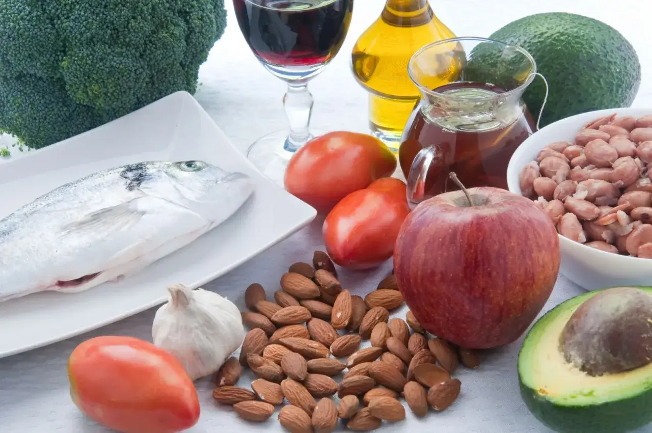 Składniki zdrowej diety na obniżenie cholesterolu: ryba, brokuły, awokado, jabłko, pomidory, czosnek, migdały, fasola, oliwa z oliwek.